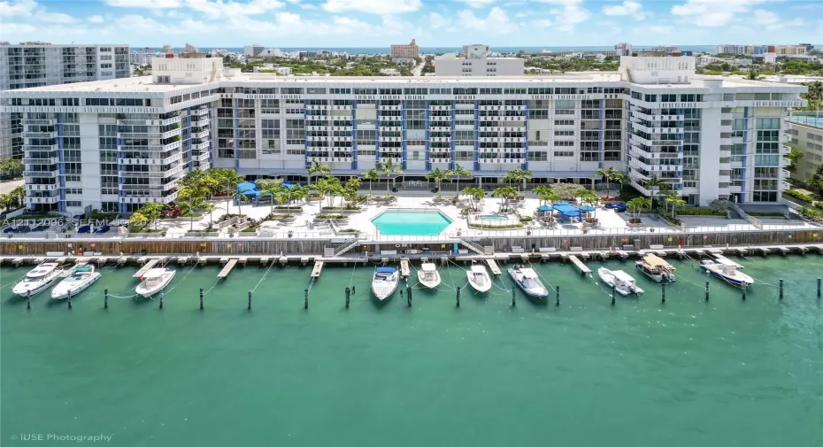 Waterfront multi-story residential building featuring a private deep-water dock, integrated swimming pool, spa, and exterior balcony access for residential units
