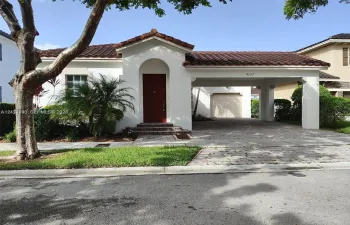 Stucco exterior featuring a tiled roof, arched entryway, brick-accented front steps, and a paved carport