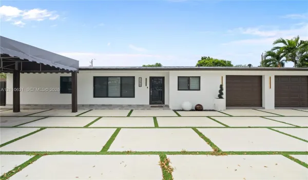Single-story exterior featuring white stucco finish, dual brown garage doors, a covered carport, and concrete paver driveway with integrated turf strips
