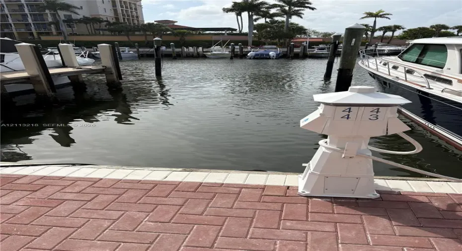 Private boat slip with brick-paver docking area, mooring pilings, and dedicated shore power pedestal
