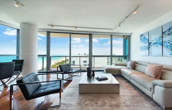 Floor-to-ceiling glass windows, wood-finish flooring, recessed track lighting, and a private balcony