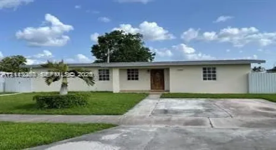 Single-story residence featuring a smooth stucco exterior, multi-pane windows, a centered wood-finish front entry door, and a concrete driveway