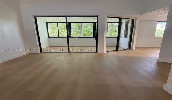 Wood-finish flooring throughout, floor-to-ceiling glass sliding doors, and a glass-enclosed interior balcony