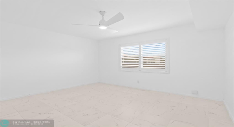 Before Virtually Staged. Large bedroom with beautiful plantation shutters. Neutral paint and light and bright space!