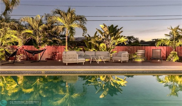 Tropical Fenced in Private Backyard with Heated Pool, uplighting, outdoor dining table, lounge chairs and plenty of seating/hammocks.