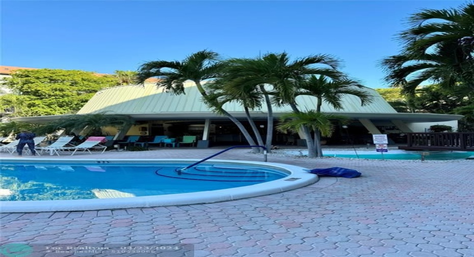 Huge covered area by pool offers seating and bar.