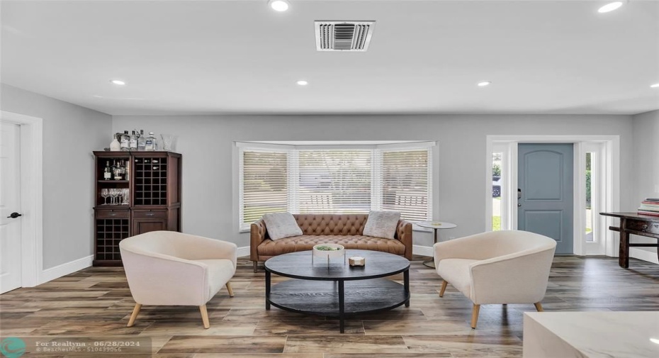 Living room offers a bay window, hi-hat lighting and wood tile flooring