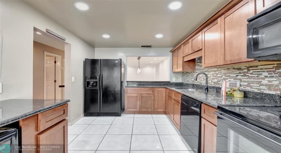 Large kitchen with all wood cabinets, granite countertops, and snack counter pass thru. wine cooler to bottom left freshly painted