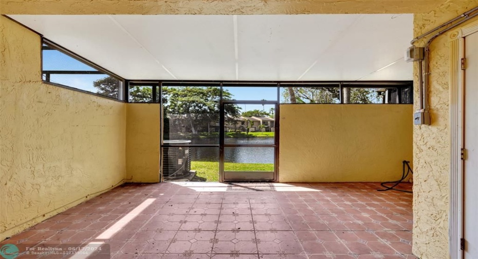 Tiled, hard roofed, and screened patio to enjoy the wide lake view.  to the right is a storage room which has shutters for all the windows even for the impact windows. there is bar that hangs on the other wall and hooks for a hammock to relax