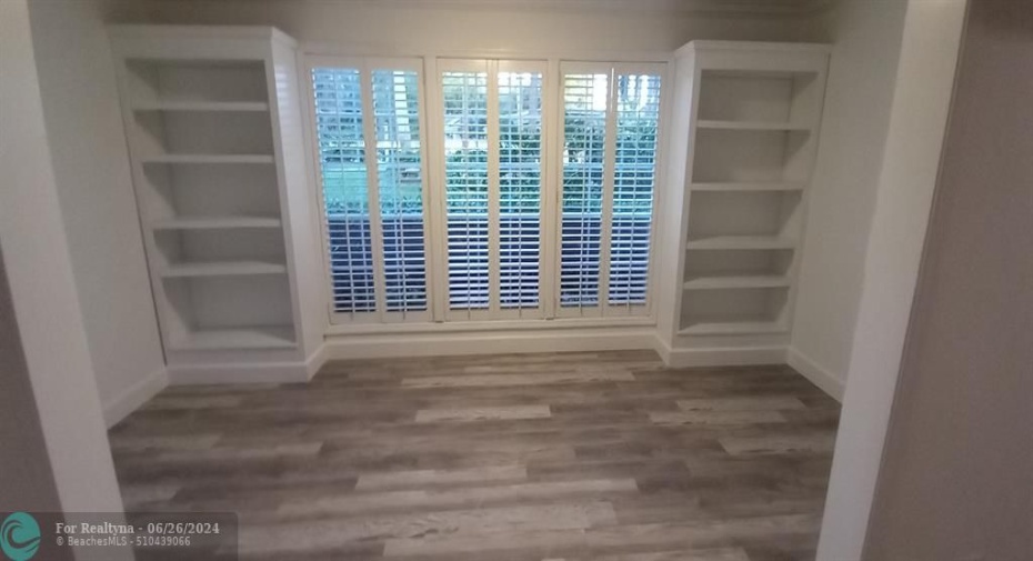 Sunroom with built-in bookcases and plantation shutters