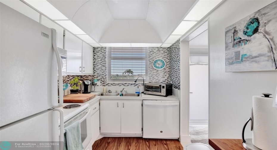 KITCHEN WITH WHITE APPLIANCES: REFRIGERATOR, ELECTRIC RANGE, DISHWASHER