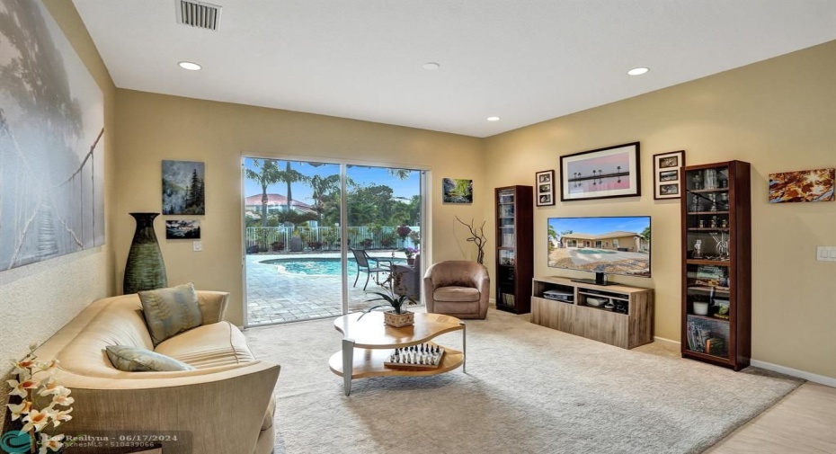 This open and inviting living area seamlessly blends indoor and outdoor living. Large sliding glass doors bathe the space in natural light and offer a stunning view of the inviting pool area. The glass doors create a perfect place to relax and unwind while still feeling connected to the outdoor oasis.