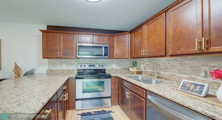 KITCHEN: Up-close stainless steel appliances, marble island, countertops and glass back splash.
