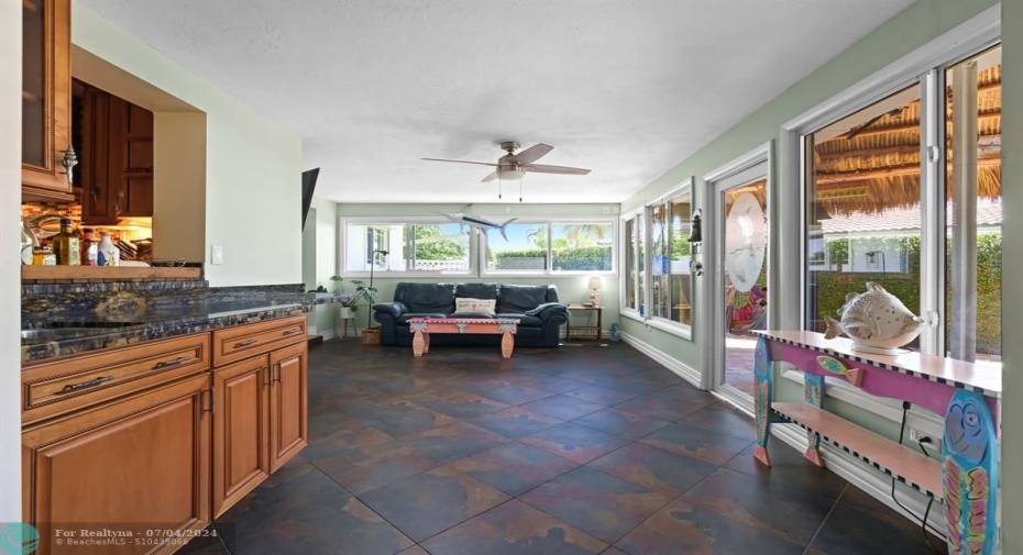 Wet bar and fantastic, bright Florida room that runs along the south side of the home and leads out to back patio/tiki area and waterfront