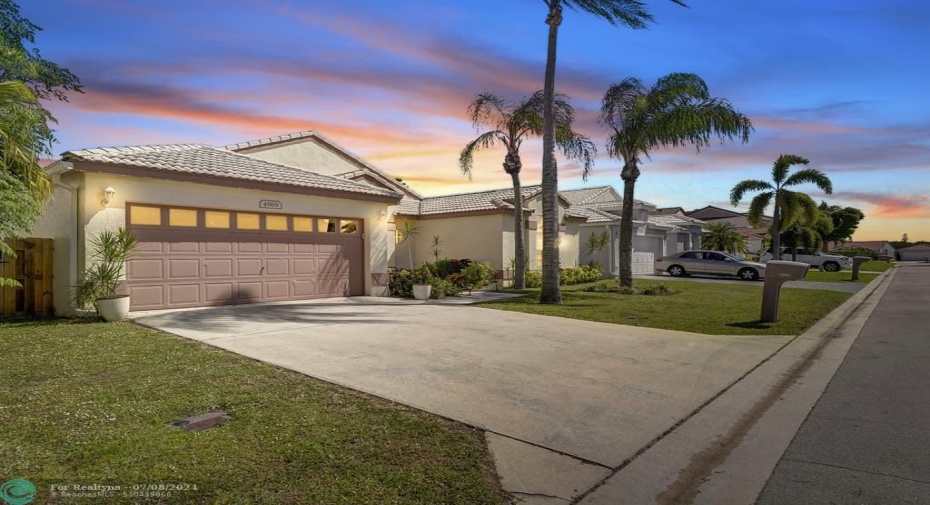 Imagine pulling into the spacious driveway of 4969 Broadstone Circle, a sunny haven lined with mature palm trees. Step out and feel the warm Florida air kiss your skin. The two-car garage, complete with a future-friendly 240-volt outlet, welcomes your electric car, ready to replenish its energy for tomorrow's adventures. And just beyond the inviting entryway, a world of comfort and sunshine awaits.