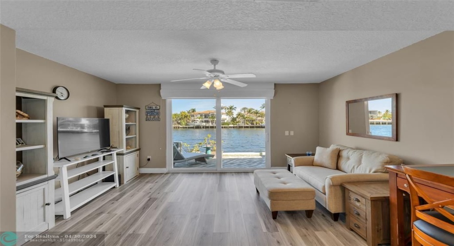 Wood like flooring and overhead ceiling fan offered in living room / dining room area