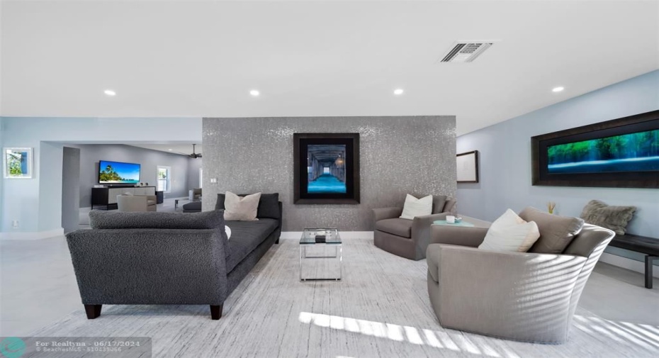 Oversized Living room with elegant and deep sectional, wall mounted smart TV, hurricane impact windows with plantation shutters to create dark or light at your finger tips.