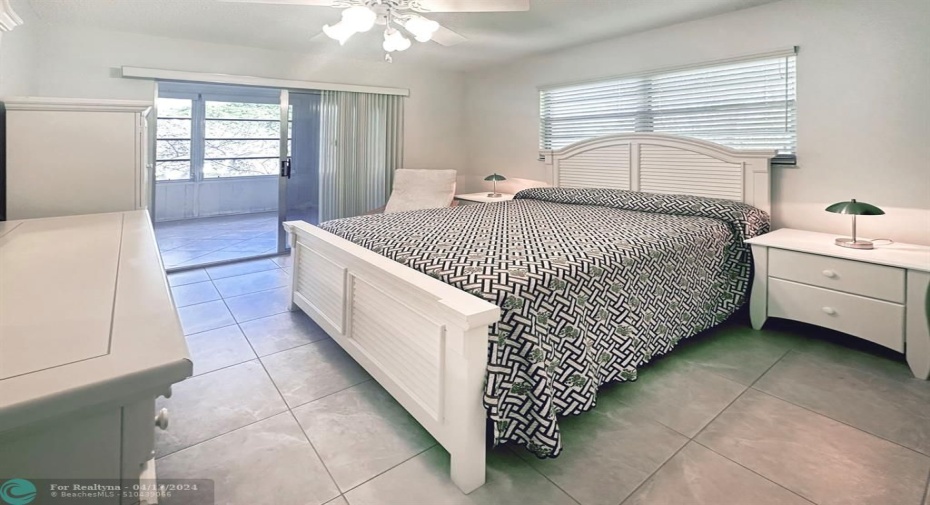 Natural Light, Tile Floors & Ceiling Fan Create a Florida Living Space in this Primary Bedroom.
