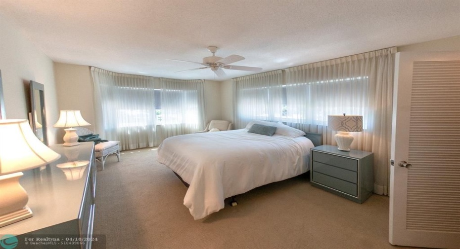 Large guest bedroom with a sitting area by the bay window
