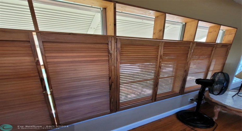 Living room with hardwood flooring and custom-made wooden bifold shutters