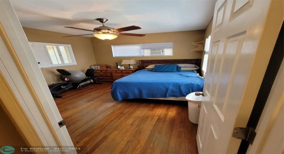 Primary bedroom hardwood flooring and plantation shutters (partial)