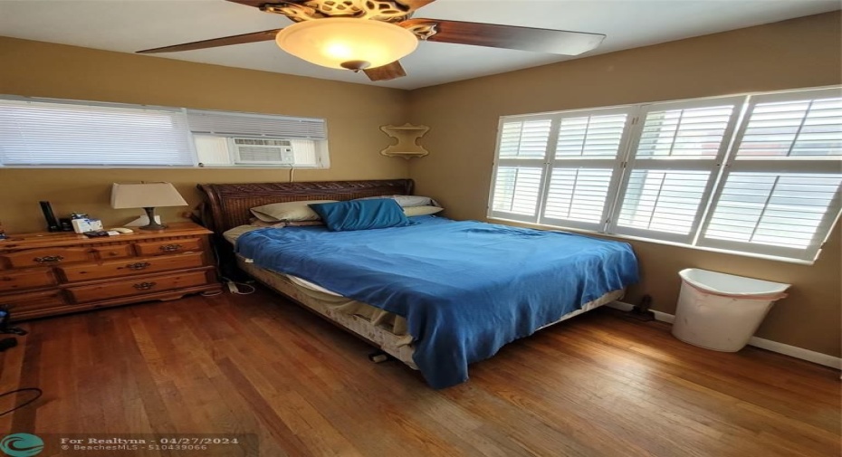 Primary bedroom hardwood flooring and plantation shutters (partial)