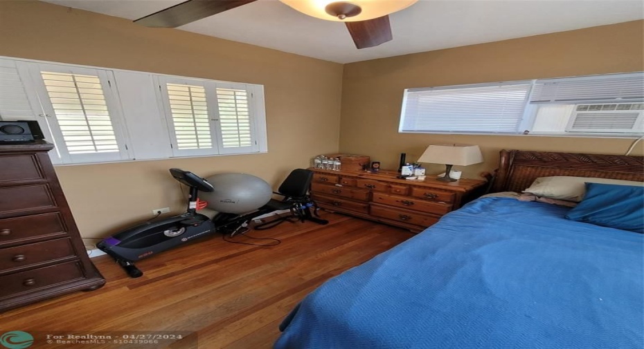 Primary bedroom hardwood flooring and plantation shutters (partial)