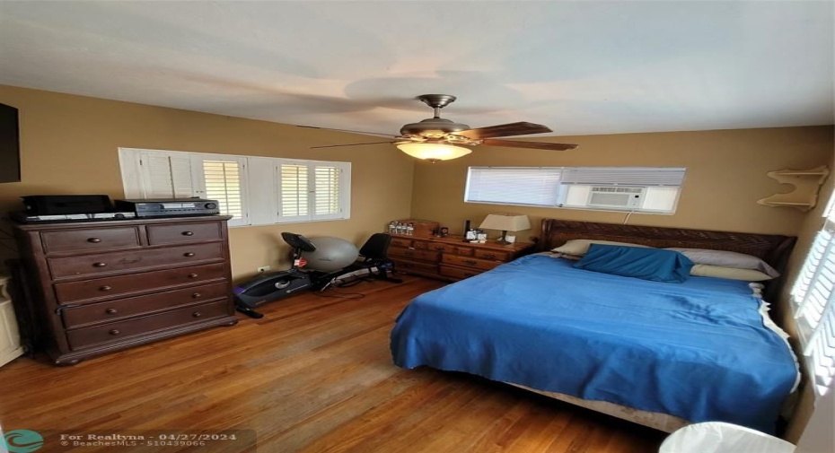 Primary bedroom hardwood flooring and plantation shutters (partial)