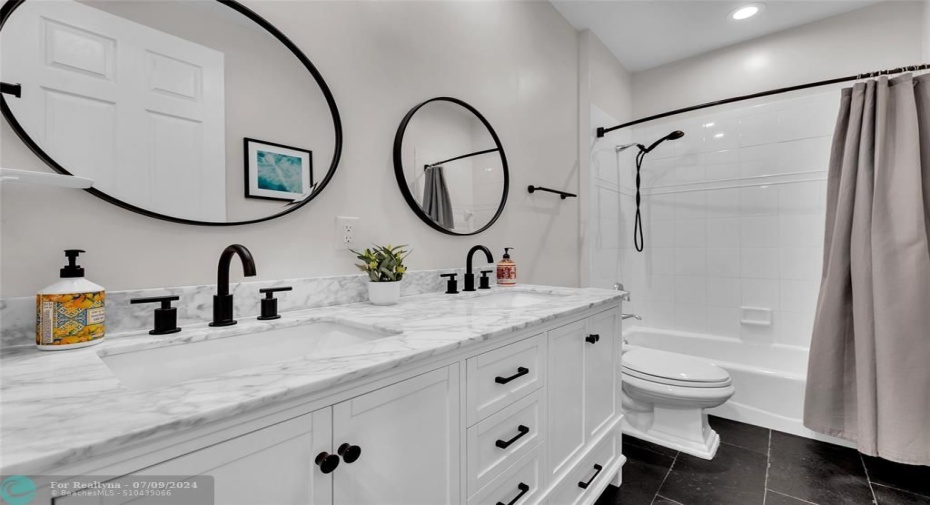 Second Bathroom with tub/shower combo and quartz counters with double vanity is located in hall for guest bedrooms