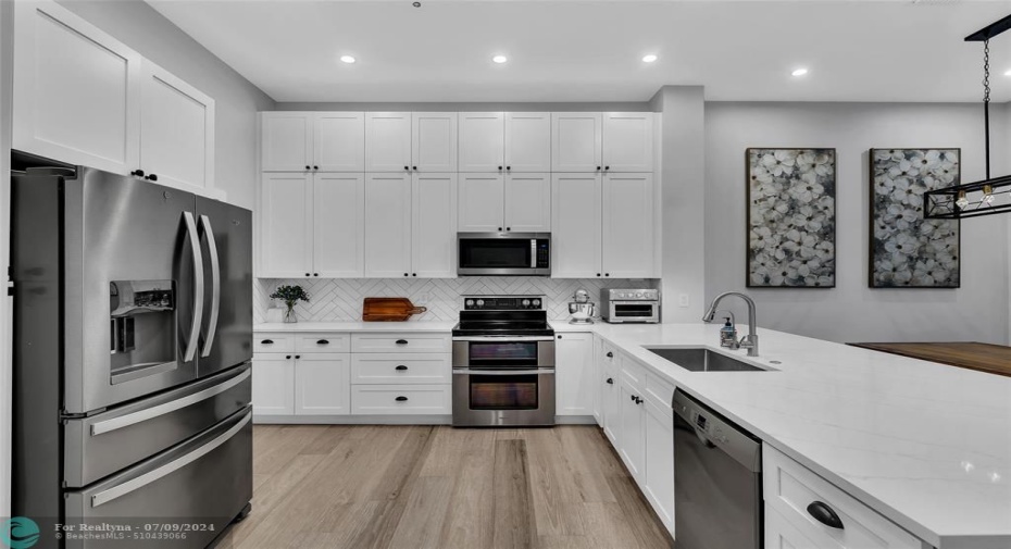 Beautifully updated open kitchen with white shaker cabinets, quartz counters, stainless appliances and more