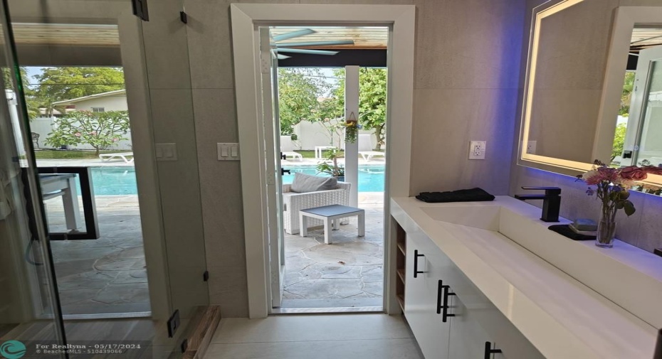 The primary bath has a door that leads out to the pool and the yard. There is also a roomy closet to the right of the sink