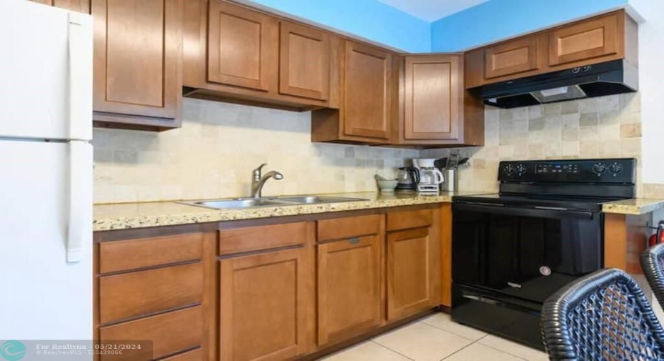 The kitchen has appliances including a refrigerator and basic kitchen utensils.