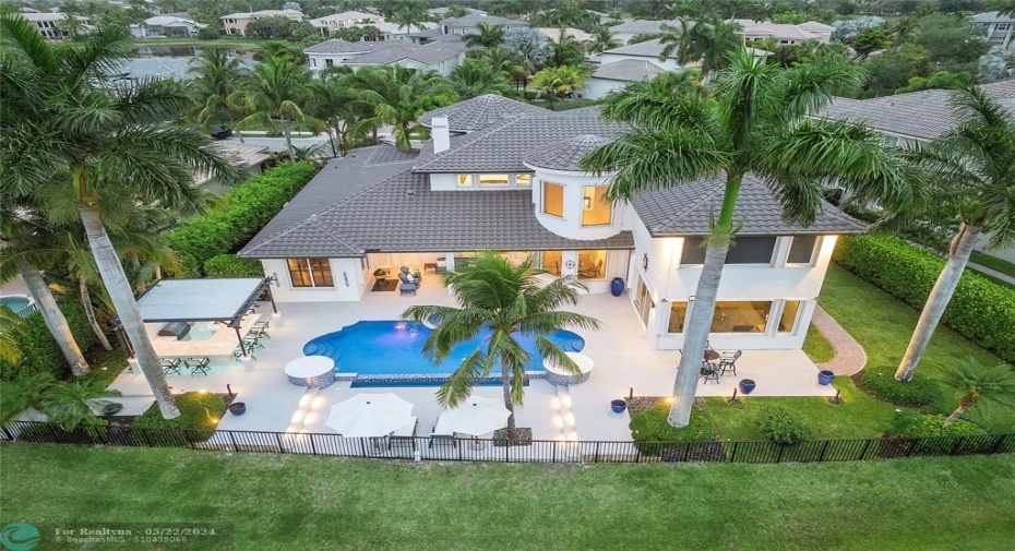 An Aerial view of this beautiful Castle with a brand new (Tobacco roof) framed by 4 Royal Palm Trees and doggie run down the side of the home..all fenced in