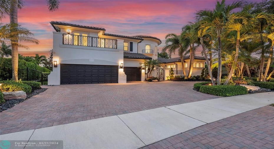 Spectacular nightime view of the front of the home with center island of Palm Trees on driveway