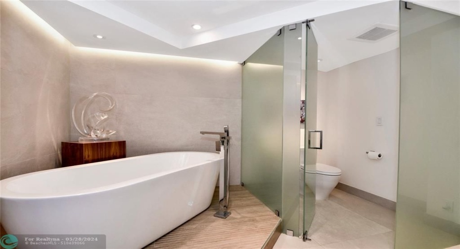 Primary Bathroom: The toilet is separated by opaque glass walls and door.