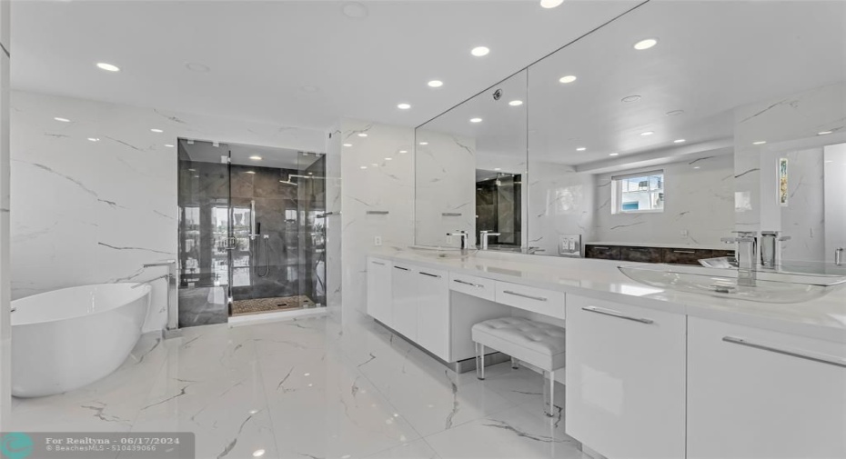 Master bathroom with double vanities, a stand alone tub and large walk in shower with marble flooring and walls