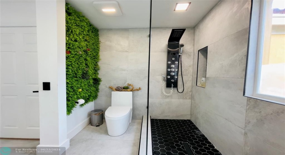 Overall, this bathroom combines modern design with functional elements, creating a relaxing and aesthetically pleasing space. The integration of natural elements, like the green wall, adds a unique and refreshing touch, making it stand out as a luxurious and inviting bathroom.