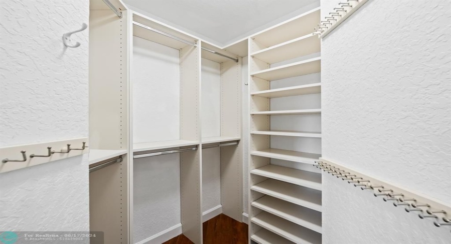 Primary suite walk-in closet featuring custom built out cabinerty