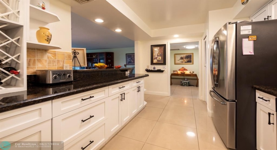 granite counters, stainless steel appliances, large cream colored rectified tile throughout