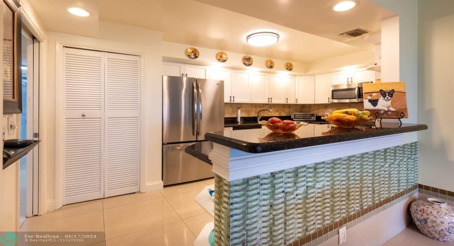 spacious open concept kitchen with bosch stack washer dryer behind louvered door