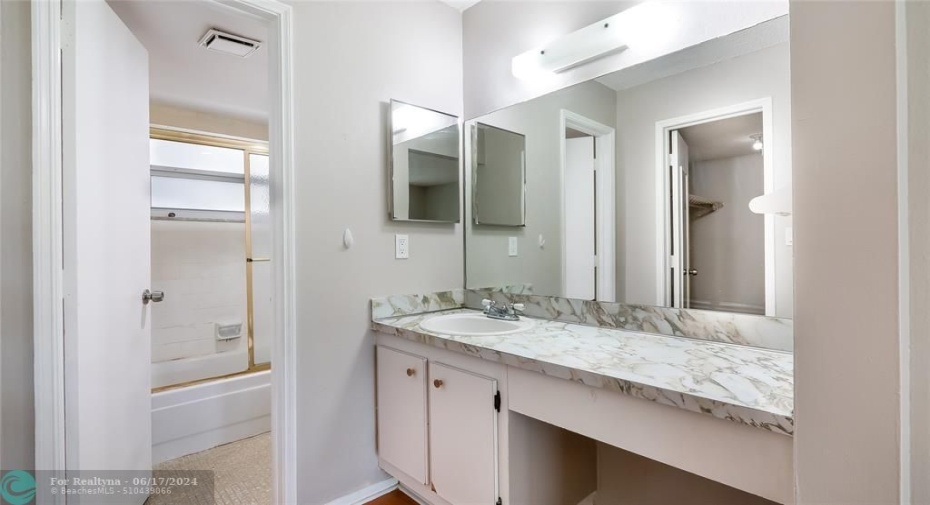 Master bathroom with spacious vanity and glass enclosed tub shower.