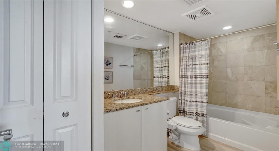 Guest bath features granite countertops and large linen closet.