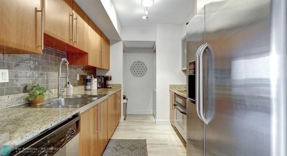 Galley kitchen with stainless steel appliances and upgraded backspace.