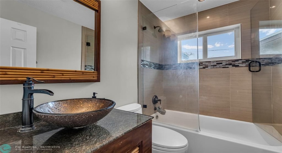 Bathroom offers a tub / shower combo with custom sink and vanity