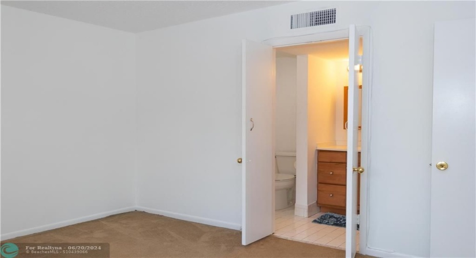 Door to ensuite primary bathroom. Carpet is now replaced with plank tile