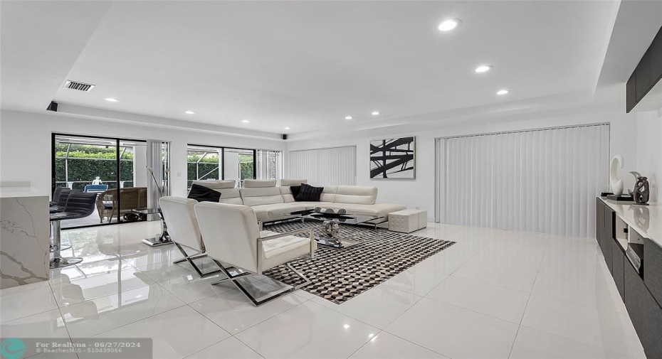 Open living room off of kitchen with tray ceiling and modern lighting.