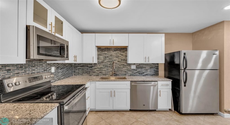 Updated kitchen with white cabinets, granite counters, tile backsplash and stainless steel appliances