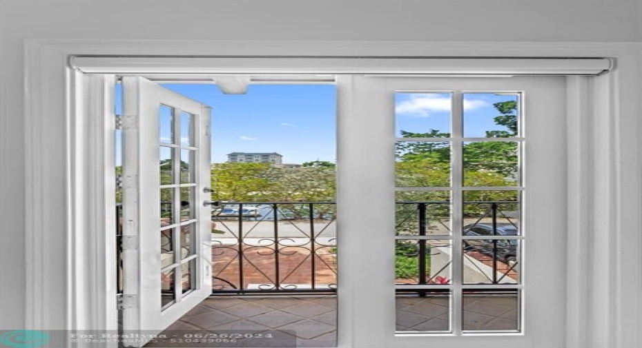 view out French doors onto patio from 2nd bedroom with great natural light
