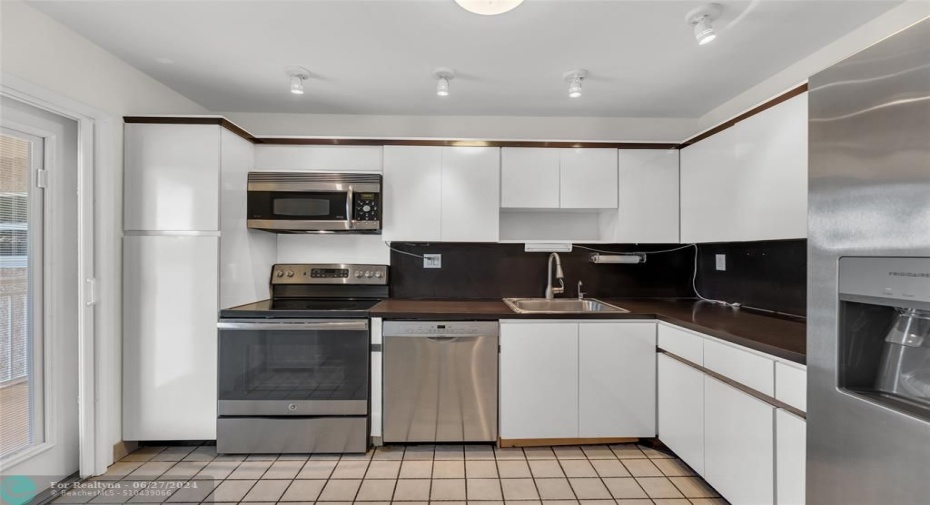 Kitchen features white cabinets, stainless appliances and great natural light from second access door