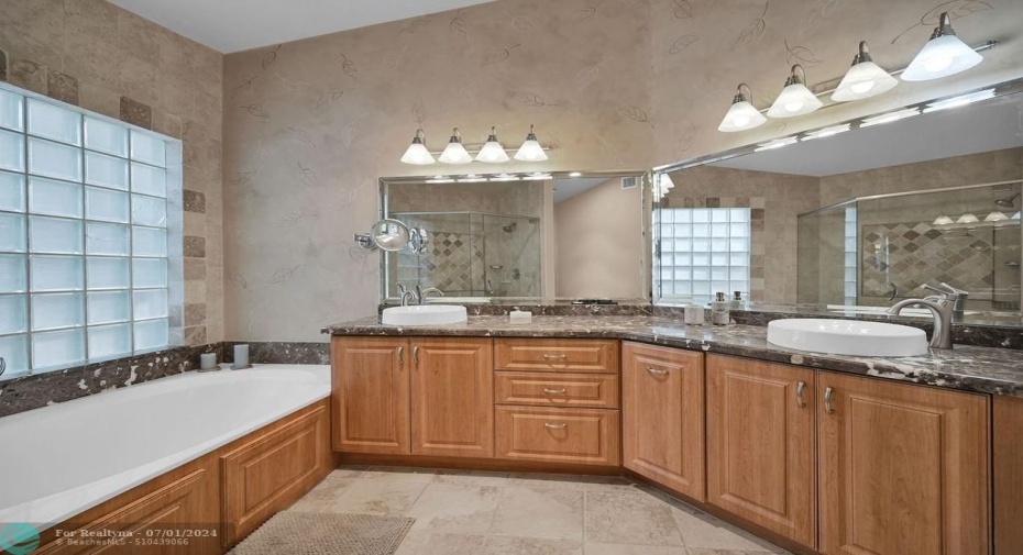 Luxury upgraded master bathroom boasts dual sinks with an abundance of vanity space, oversized soaking tub, a separate shower, glass block to bring in natural light with privacy, a linen closet, & more.